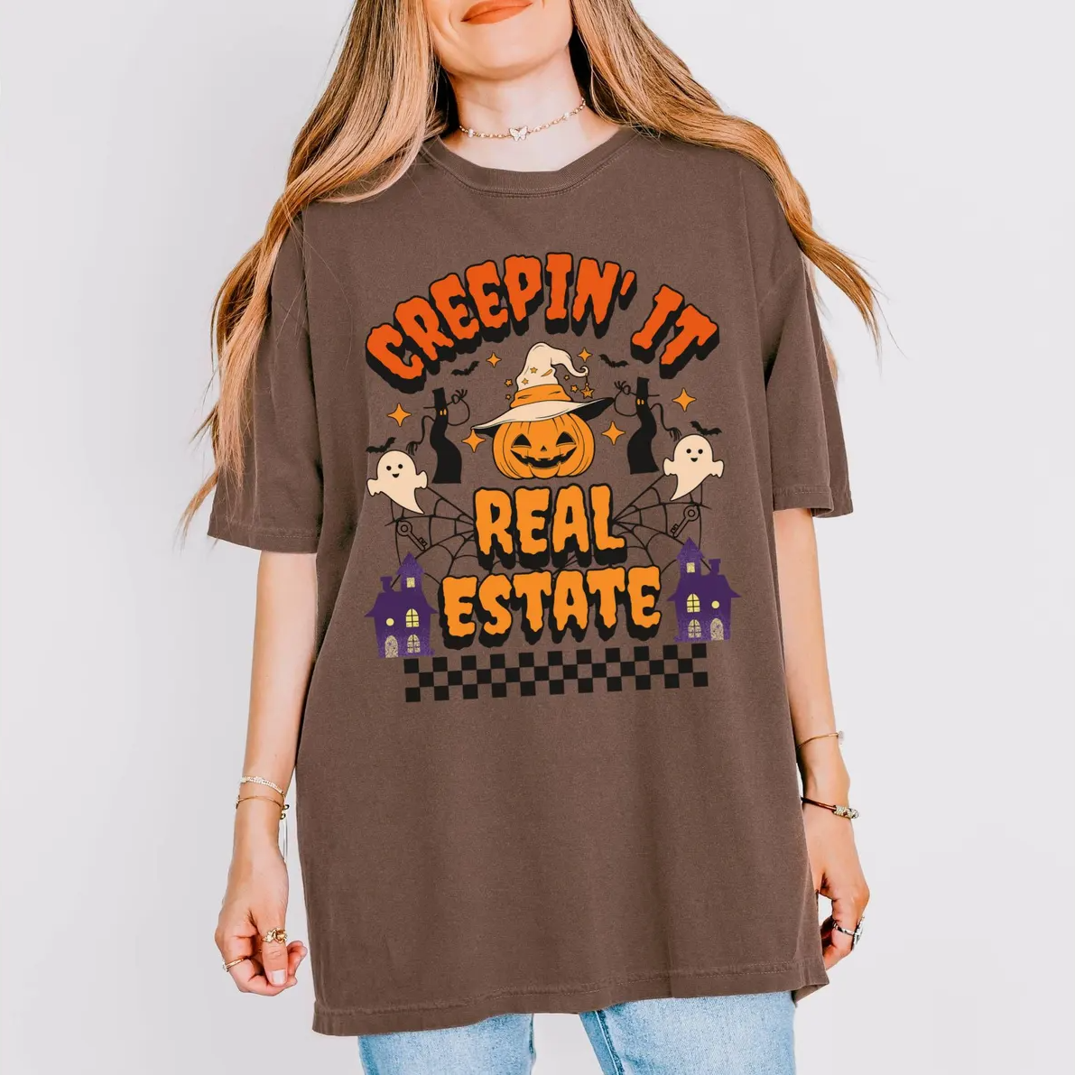 A woman wearing a brown t-shirt with a Halloween-themed graphic design.