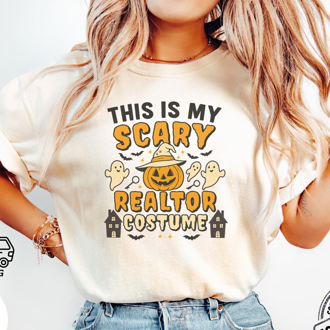 A woman wearing a white t-shirt with a Halloween-themed graphic design, including a jack-o-lantern, bats, and ghostly figures.