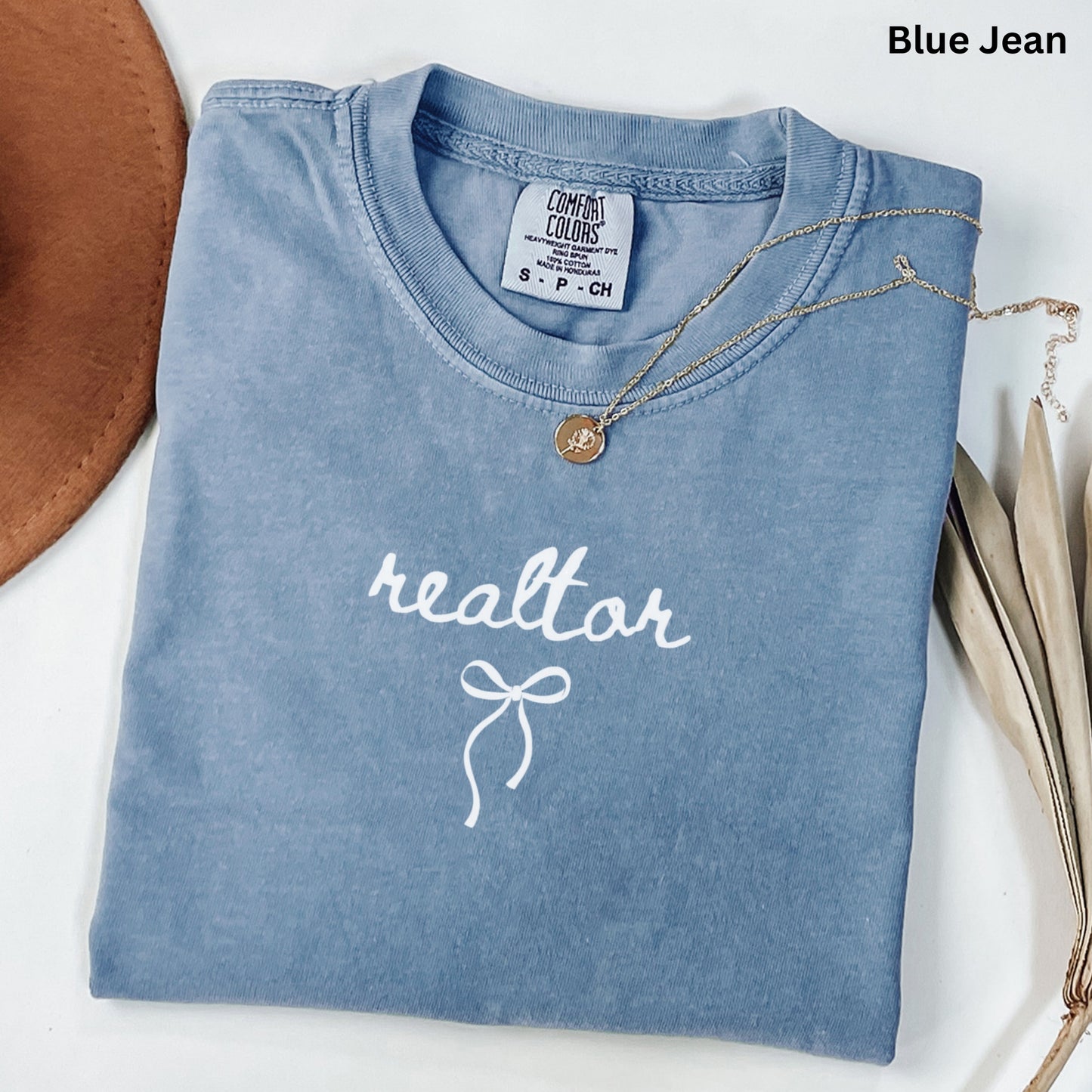 A blue t-shirt with the word "realtor" printed on it, along with a small gold medallion necklace.