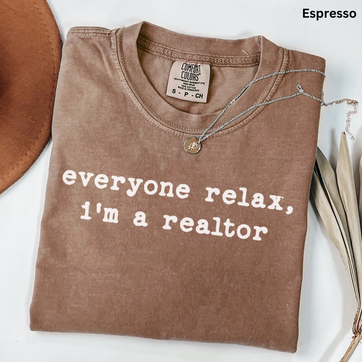 a brown t-shirt with the text "everyone relax, i'm a realtor" printed on it.