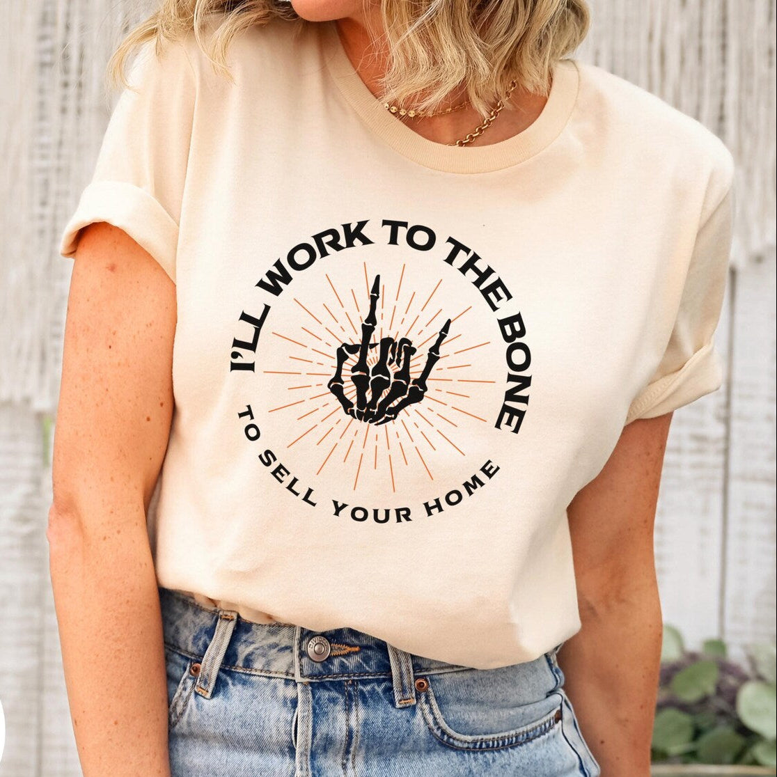 Person wearing a t-shirt with a graphic and text, standing against a wooden wall.