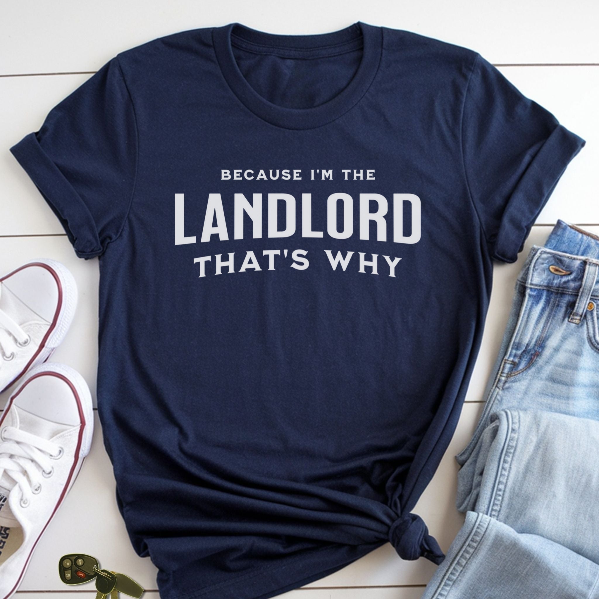 A navy blue t-shirt with the text "BECAUSE I'M THE LANDLORD THAT'S WHY" printed on it, along with a pair of jeans and white sneakers.
