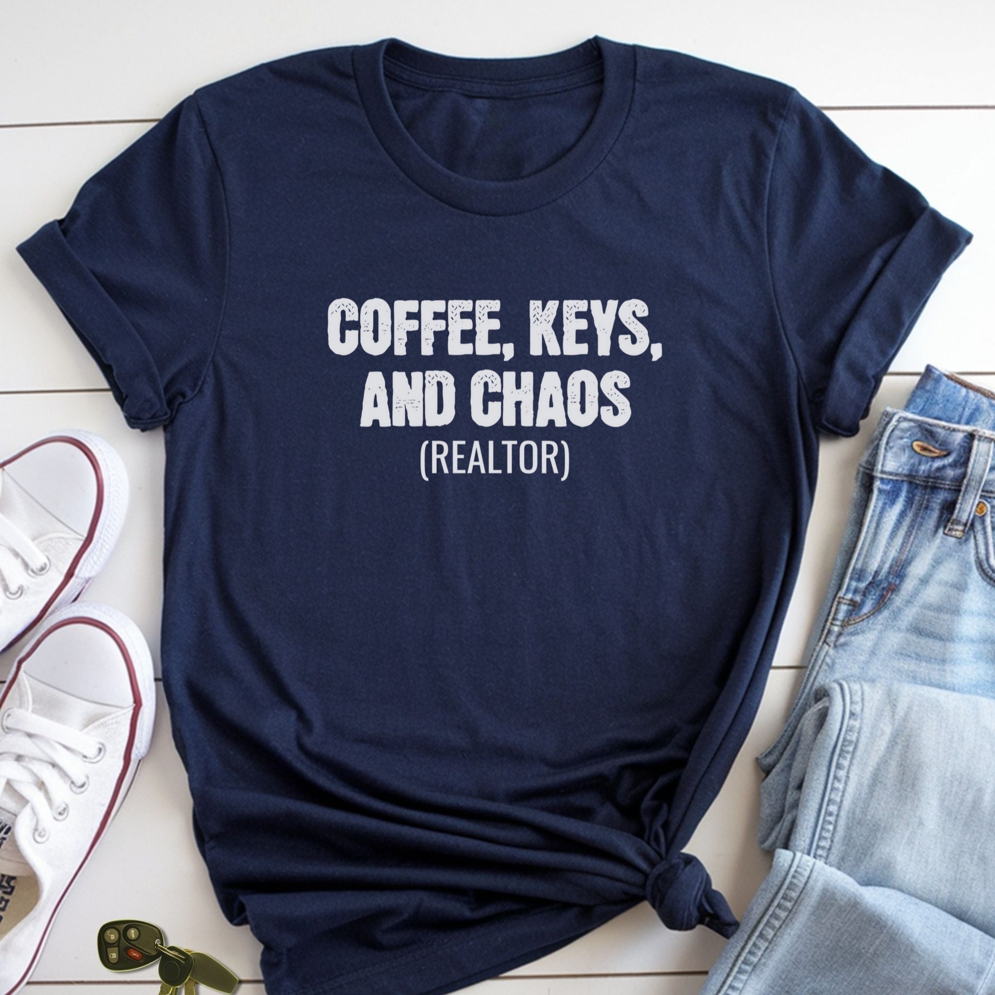 A navy blue t-shirt with the text "COFFEE, KEYS, AND CHAOS (REALTOR)" printed on it, along with a pair of jeans and a pair of white sneakers.