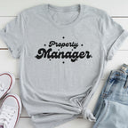 A gray t-shirt with the text "Property Manager" printed on it, along with some jeans and white sneakers.