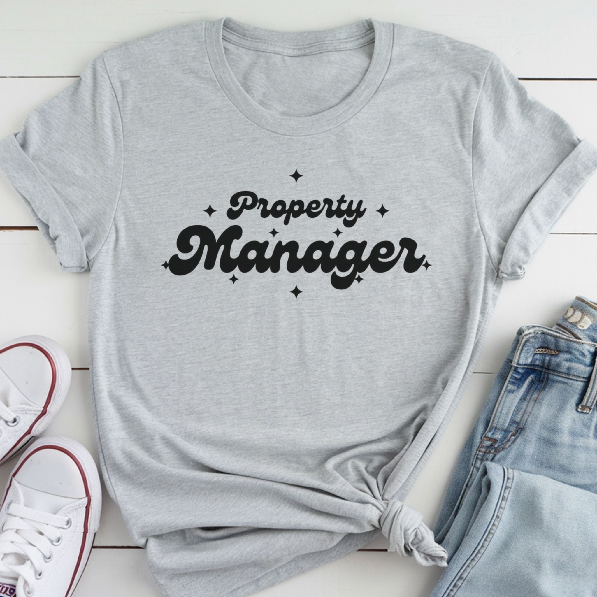 A gray t-shirt with the text "Property Manager" printed on it, along with some jeans and white sneakers.