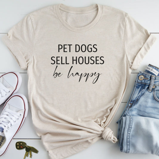 A beige t-shirt with the text "PET DOGS SELL HOUSES be happy" printed on it, along with a pair of jeans and white sneakers.