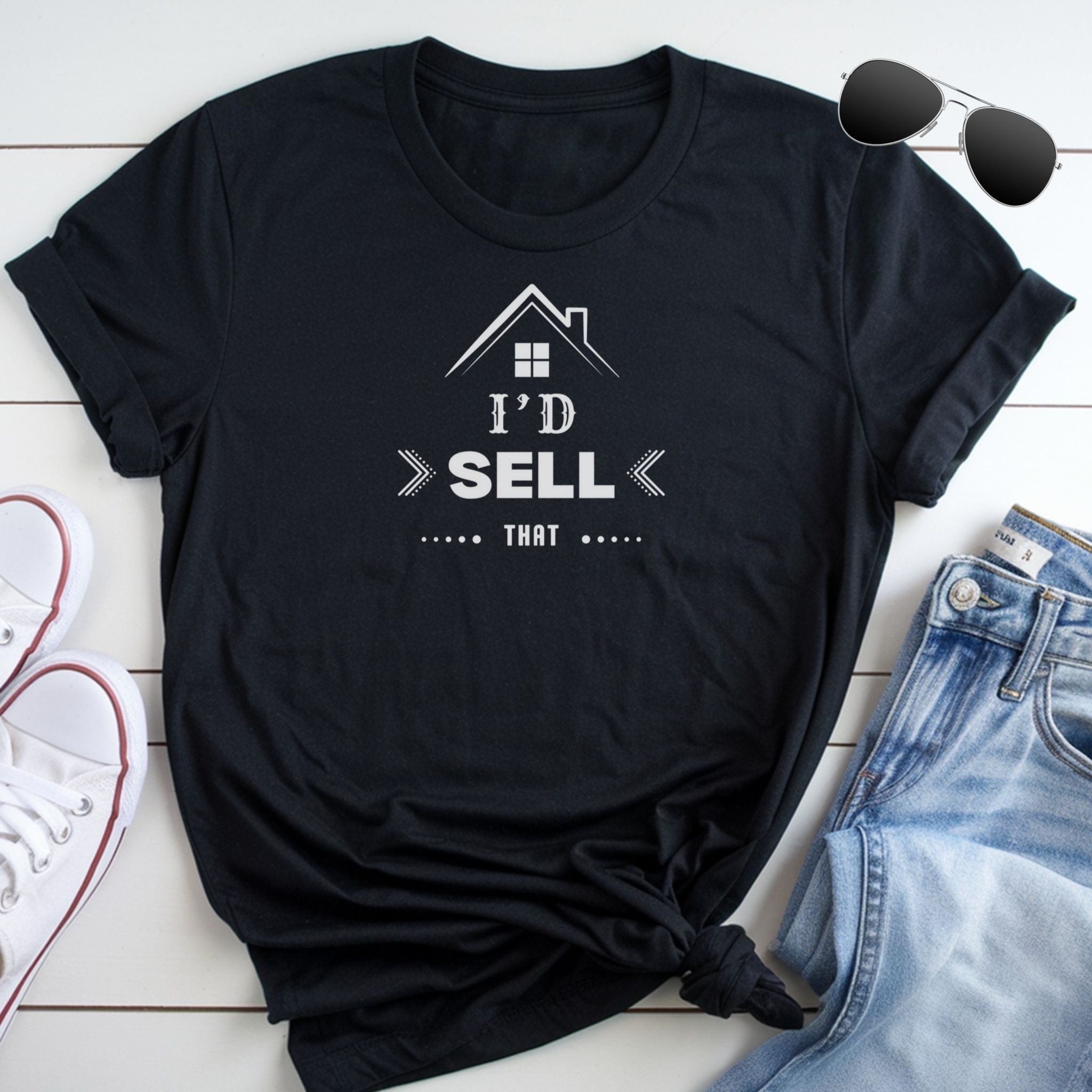 A black t-shirt with a white graphic design and text, along with a pair of jeans and sunglasses, all laid out on a white surface.