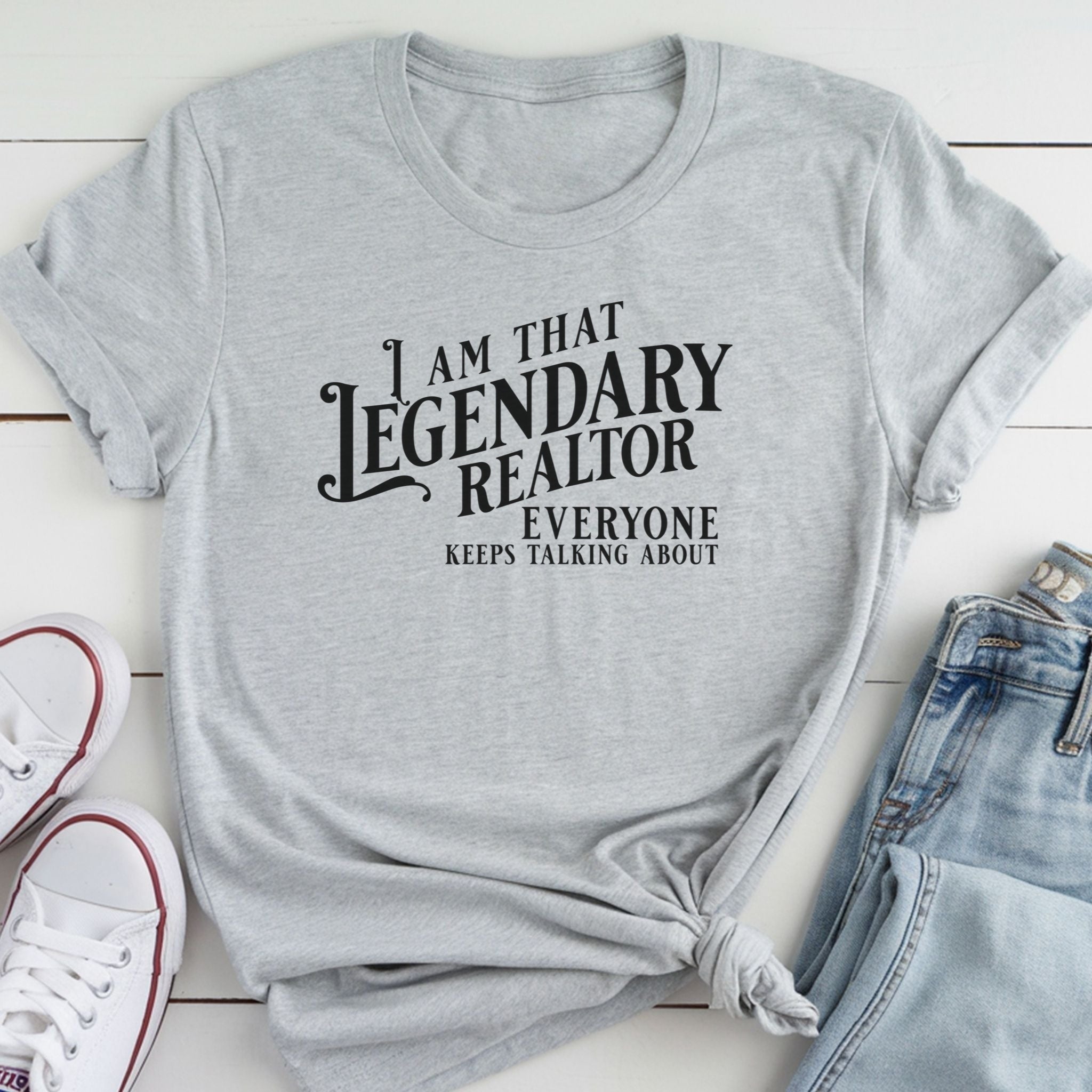 A gray t-shirt with a humorous text printed on it, along with a pair of jeans and white sneakers.