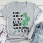 A gray t-shirt with a humorous text and cloverleaf design printed on it, along with a pair of jeans and white sneakers.