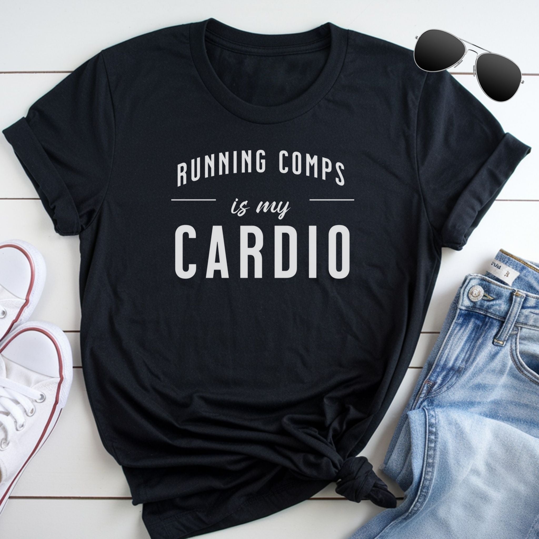 A black t-shirt with the text "RUNNING COMPPS IS MY CARDIO" printed on it, along with a pair of sunglasses and a pair of jeans.