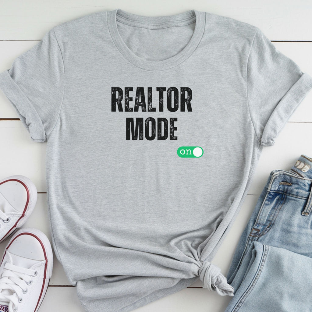 A gray t-shirt with the text "REALTOR MODE" printed on it, along with a green button that says "ON" on the right side.
