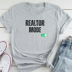 A gray t-shirt with the text "REALTOR MODE" printed on it, along with a green button that says "ON" on the right side.