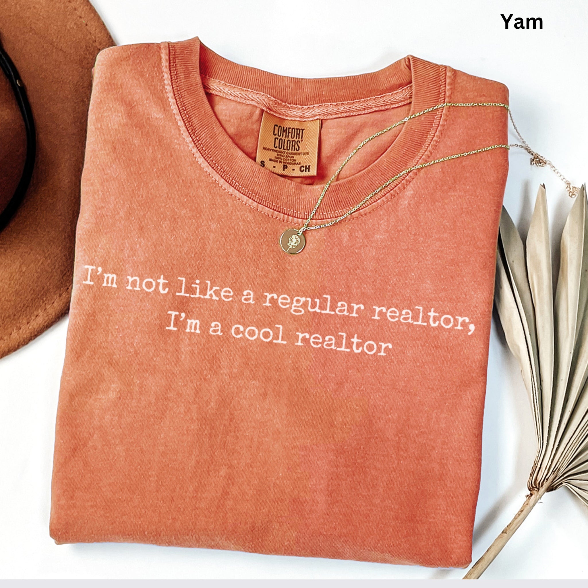 a red t-shirt with a humorous text printed on it, along with a necklace and a hat.