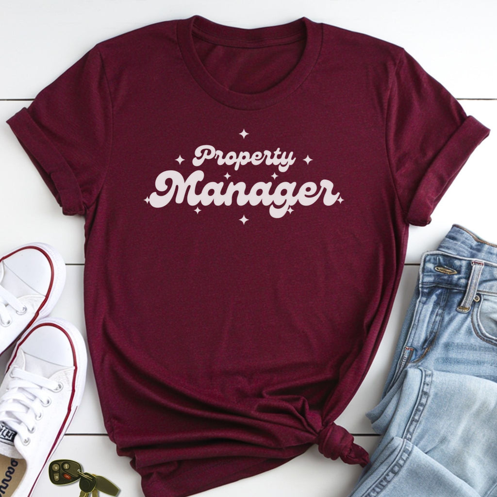 A burgundy t-shirt with the text "Property Manager" printed on it, along with a pair of jeans and white sneakers.