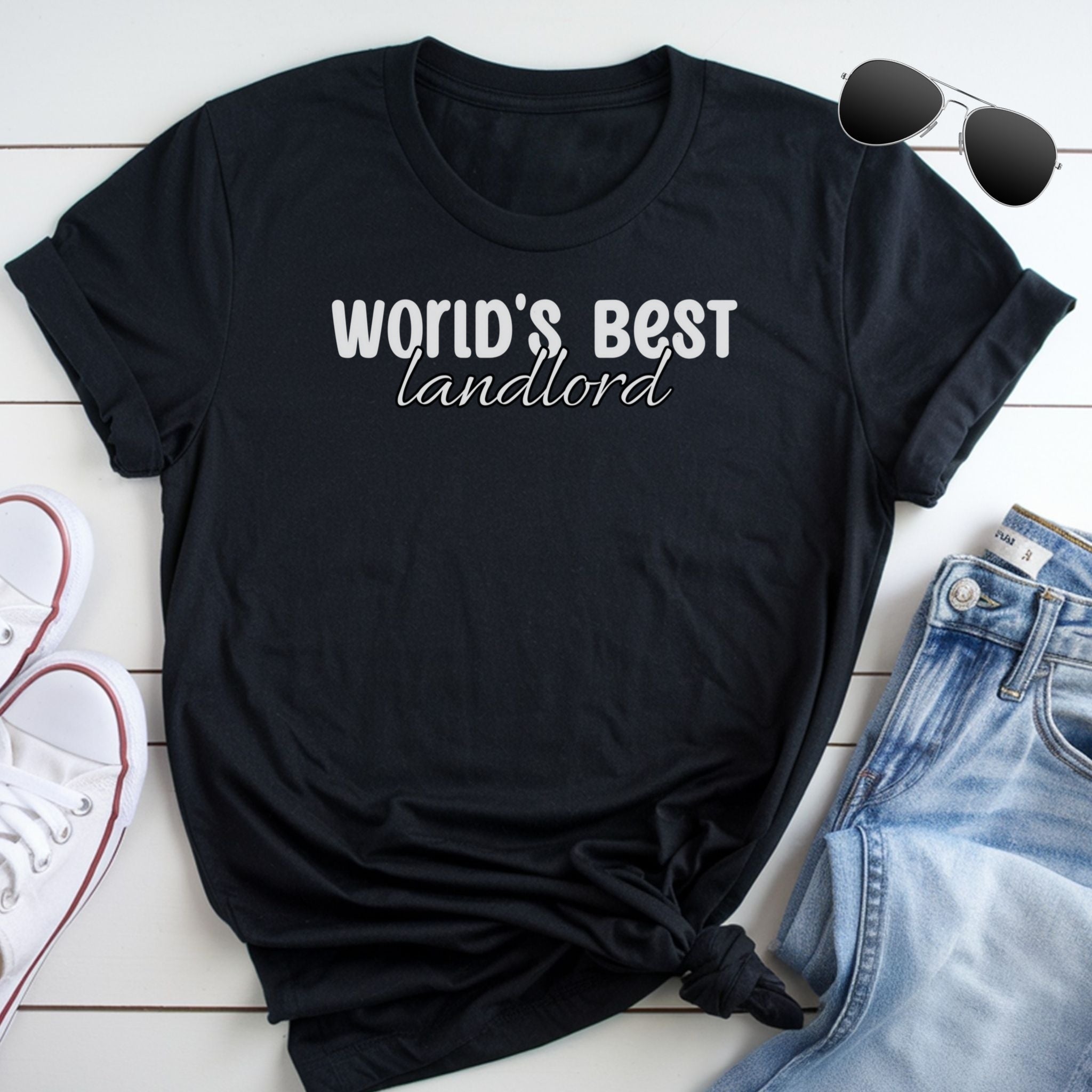 A black t-shirt with the text "WORLD'S BEST landlord" printed on it, along with a pair of sunglasses and a pair of jeans.