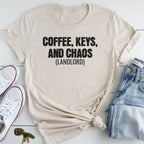 A beige t-shirt with the text "COFFEE, KEYS, AND CHAOS (LANDLORD)" printed on it, along with a pair of jeans and a pair of white sneakers.