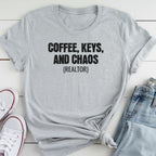 A gray t-shirt with the text "COFFEE, KEYS, AND CHAOS (REALTOR)" printed on it, along with a pair of jeans and white sneakers.