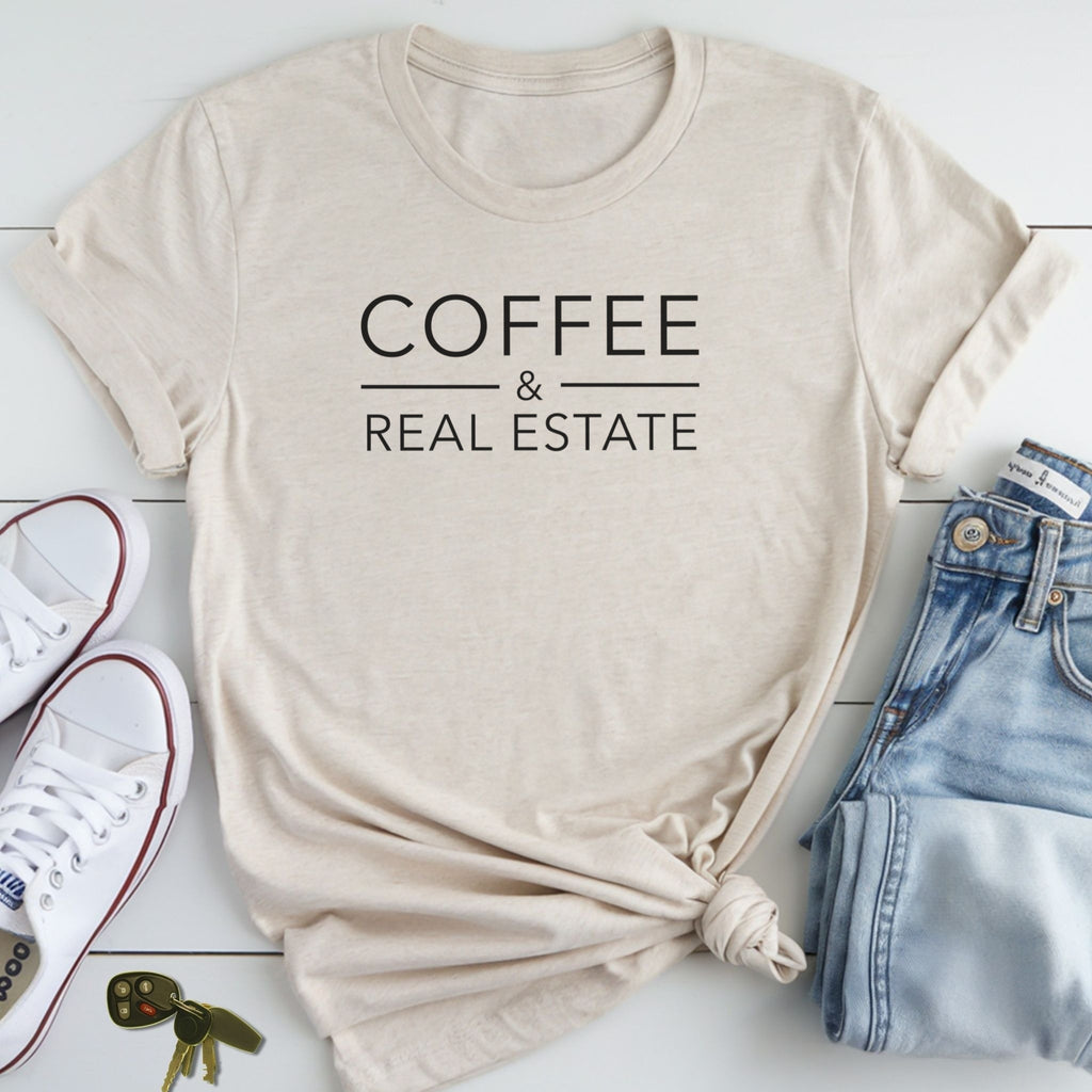 A beige t-shirt with the text "COFFEE & REAL ESTATE" printed on it, along with a pair of jeans and white sneakers, all laid out on a white surface.