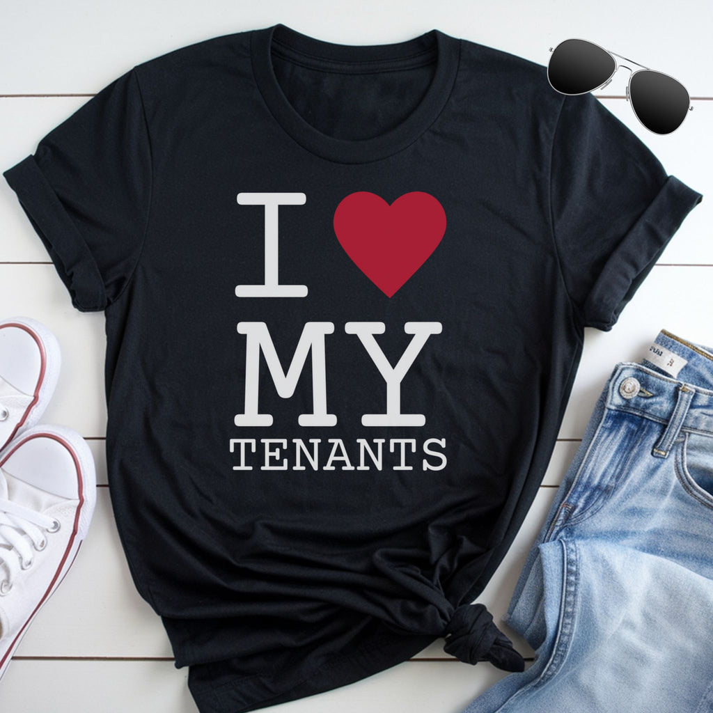A black t-shirt with the text "I ♥ MY TENANTS" printed on it, along with a red heart symbol. The t-shirt is placed on a white surface, and there are a pair of sunglasses and a pair of jeans visible in the image.