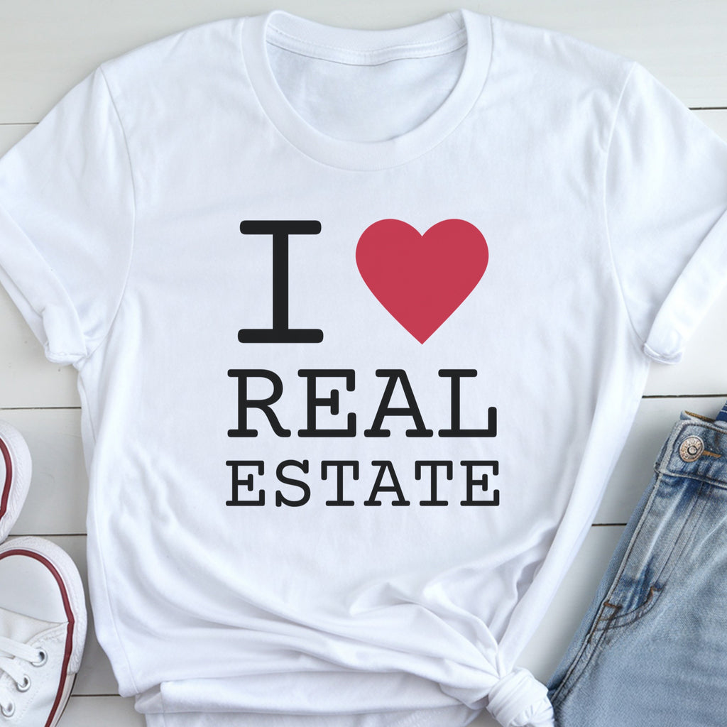 A white t-shirt with the text "I ❤️ REAL ESTATE" printed on it, along with a red heart symbol.