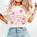 A woman wearing a white t-shirt with a graphic design printed on it, featuring various icons and text related to real estate and love.