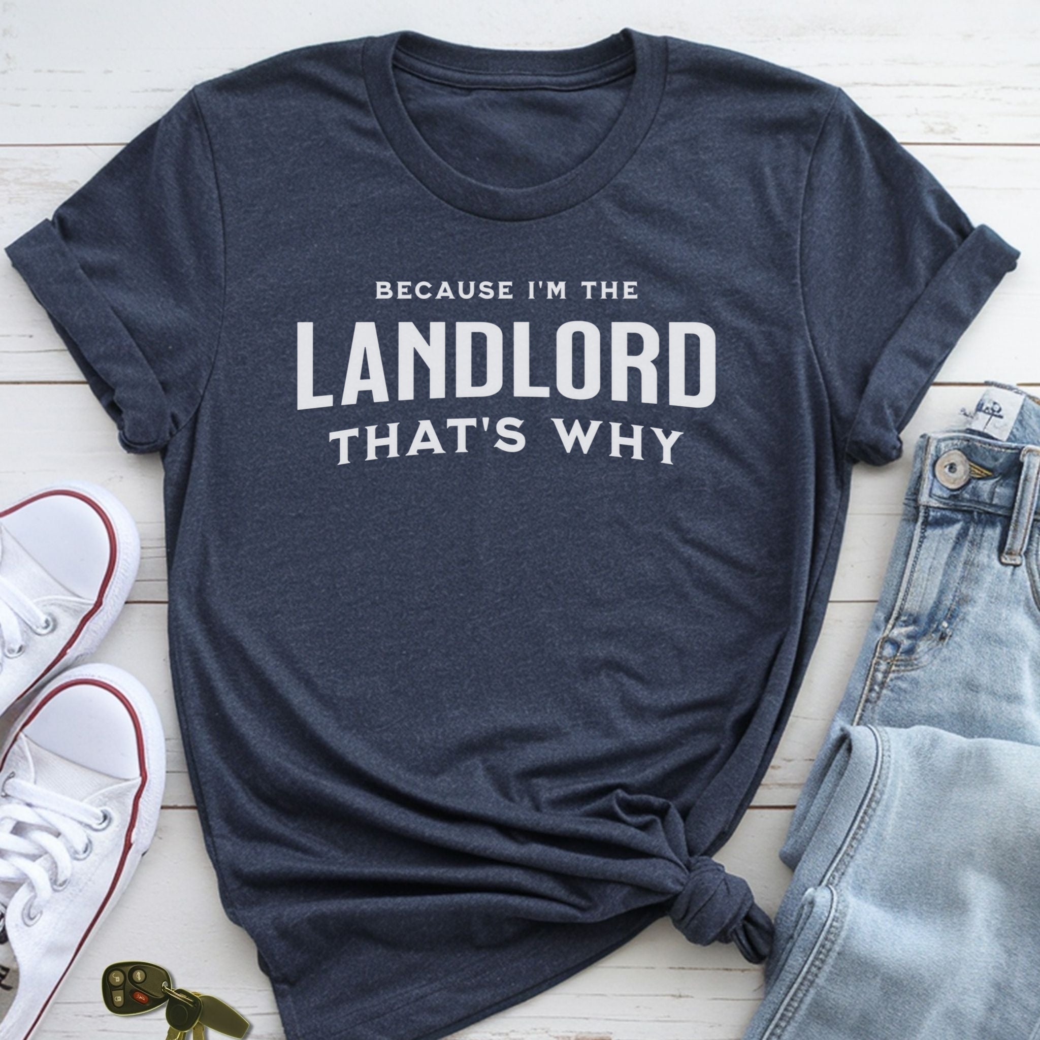 A navy blue t-shirt with the text "BECAUSE I'M THE LANDLORD THAT'S WHY" printed on it, along with a pair of jeans and white sneakers.
