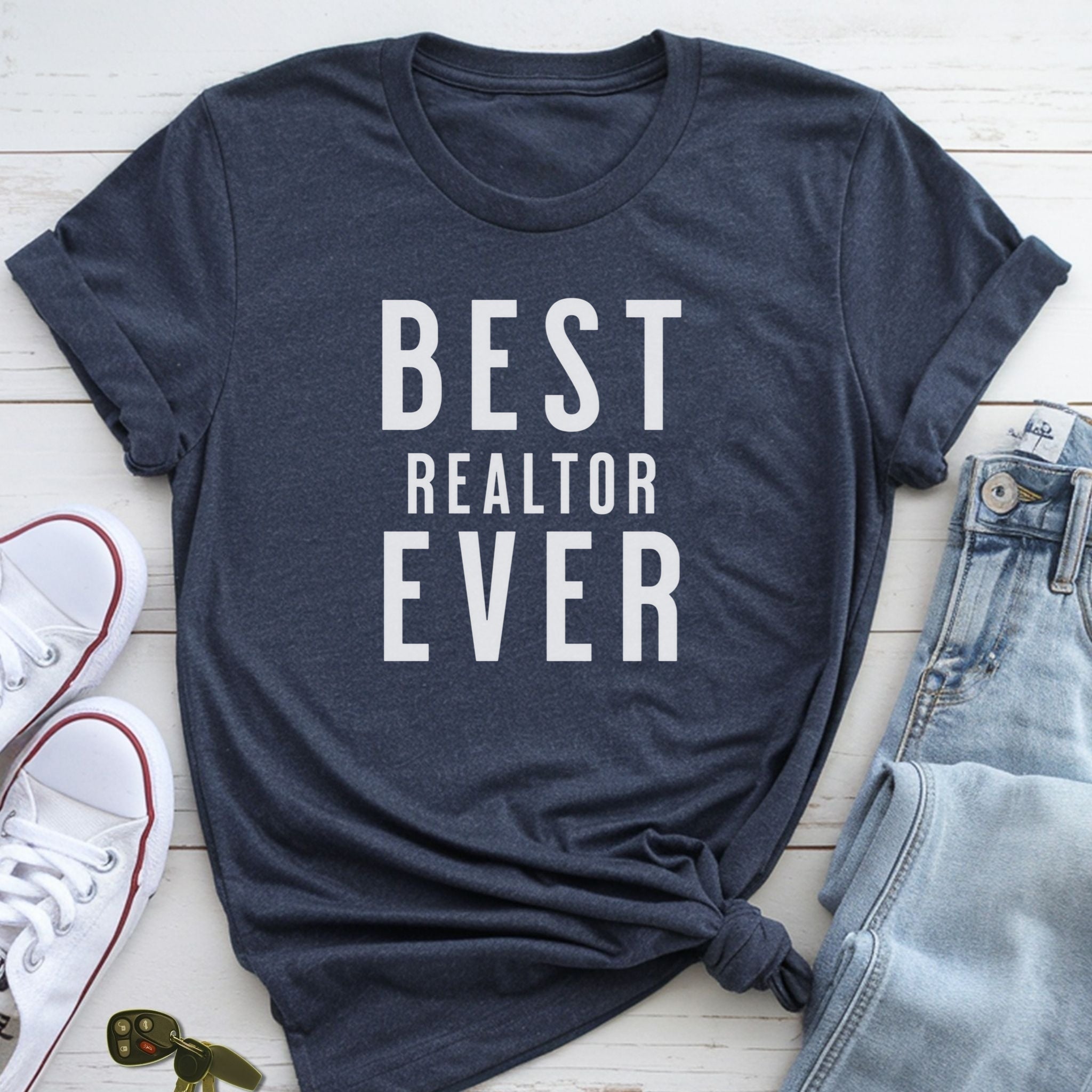 A navy blue t-shirt with the text "BEST REALTOR EVER" printed on it, along with a pair of jeans and white sneakers.