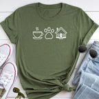 A green t-shirt with white icons of a cup, paw print, and house, along with a pair of jeans and sunglasses, all laid out on a white surface.