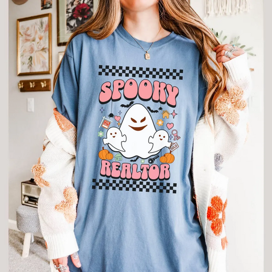 A woman wearing a blue t-shirt with a graphic design featuring a ghost character and the text "SPOKEY REALTOR".
