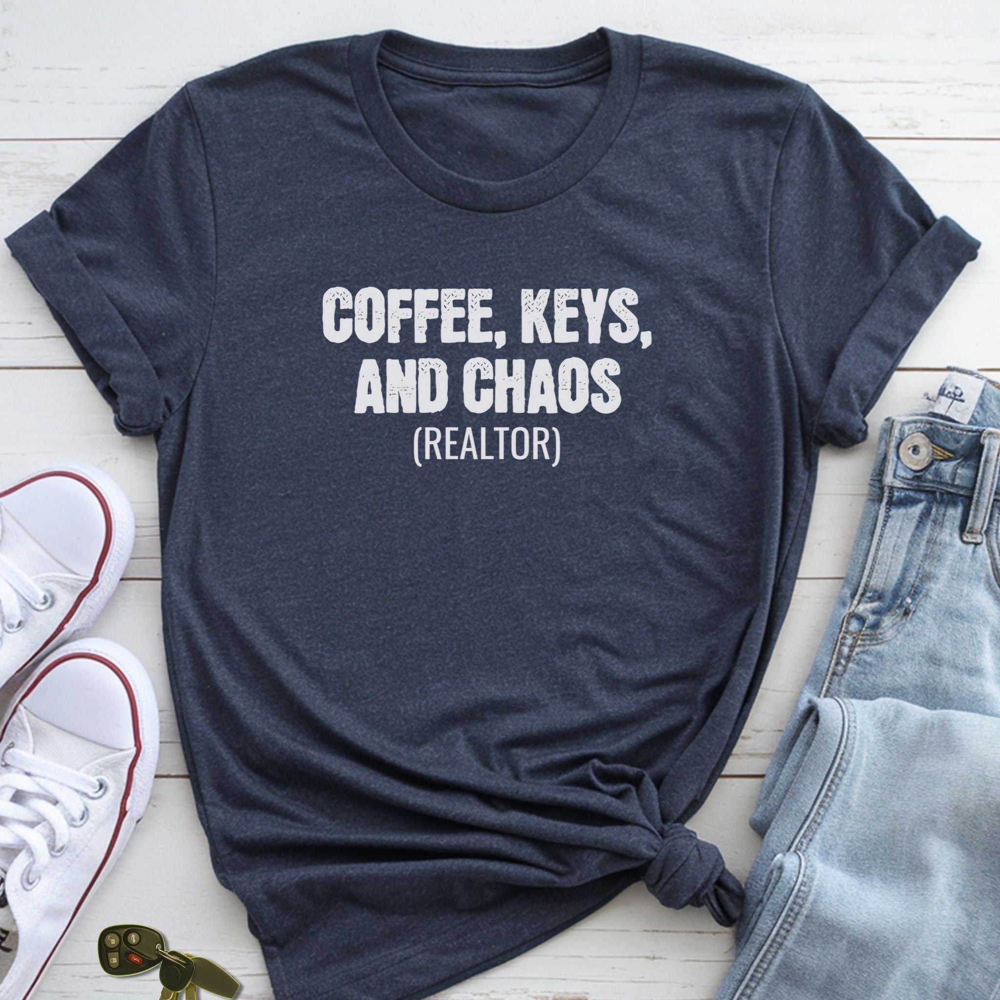 A navy blue t-shirt with the text "COFFEE, KEYS, AND CHAOS (REALTOR)" printed on it, along with a pair of jeans and white sneakers.