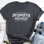 A gray t-shirt with the text "It's not easy being a property manager but here I am nailing it" printed on it, along with a pair of jeans and sunglasses.