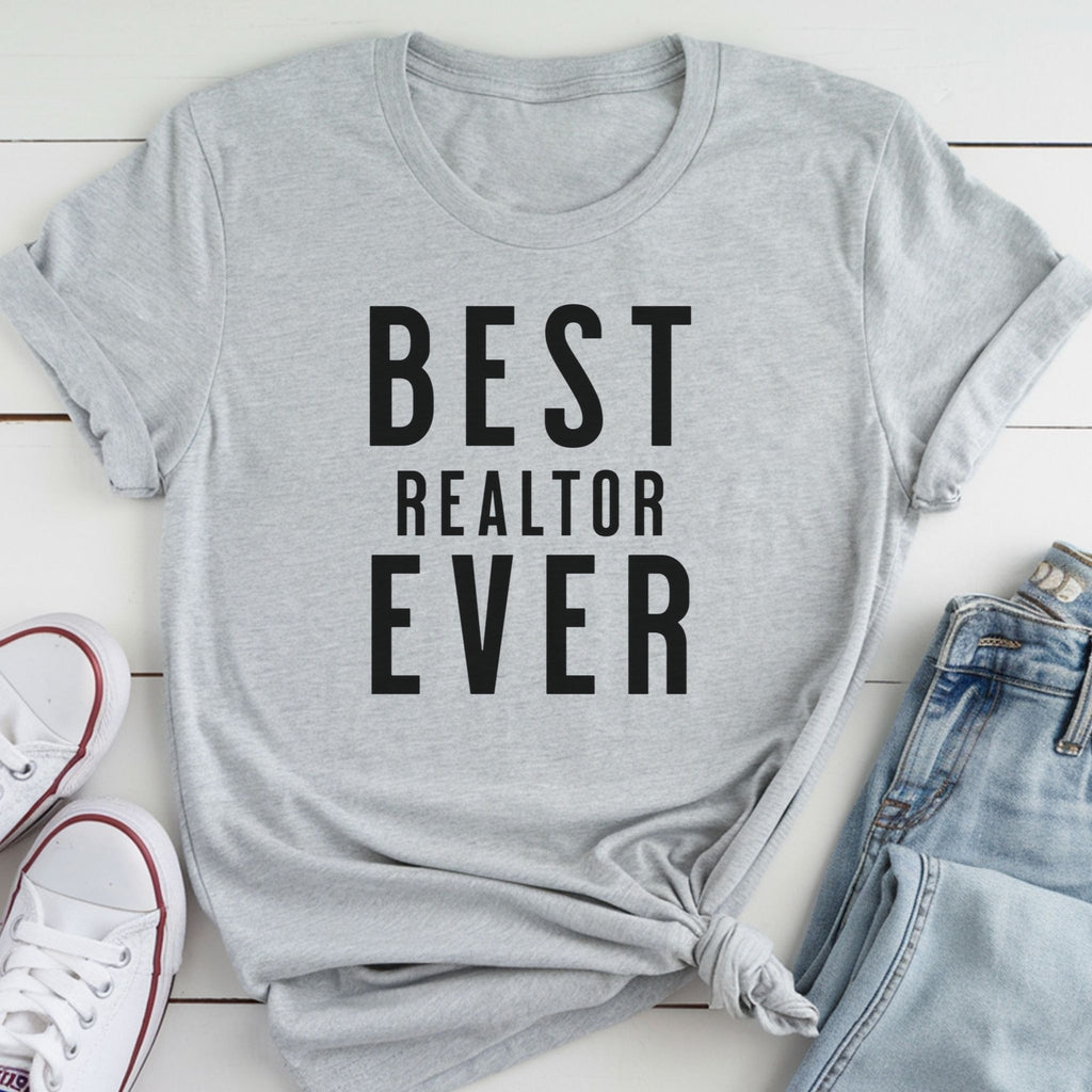 A gray t-shirt with the text "BEST REALTOR EVER" printed on it, along with a pair of jeans and white sneakers.