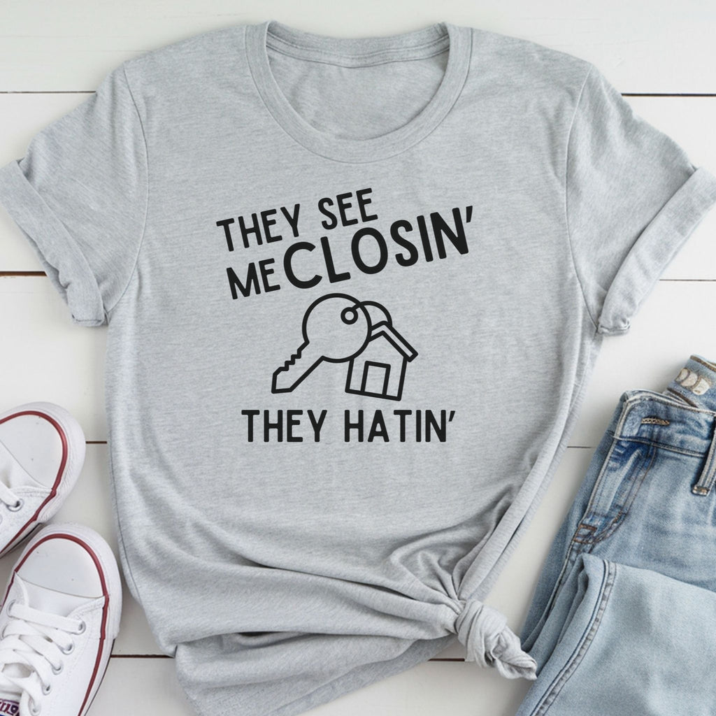A gray t-shirt with a humorous text printed on it, along with a pair of jeans and white sneakers.