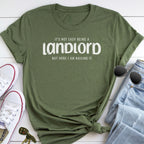 A green t-shirt with a humorous text printed on it, along with a pair of sunglasses, a pair of jeans, and a pair of white sneakers.