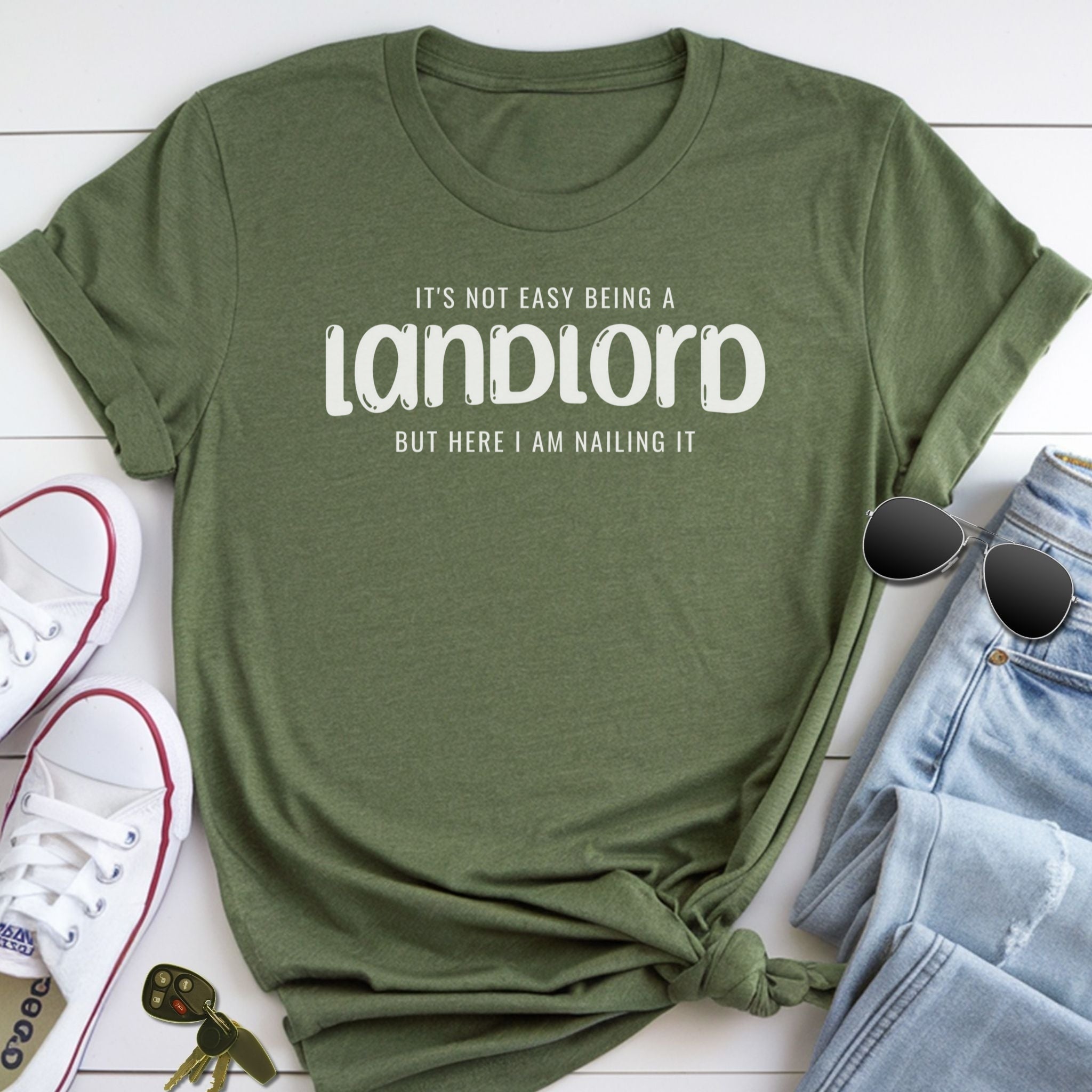 A green t-shirt with a humorous text printed on it, along with a pair of sunglasses, a pair of jeans, and a pair of white sneakers.