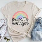 A beige t-shirt with a rainbow graphic and the text "Property Manager" printed on it, along with a pair of jeans and white sneakers.