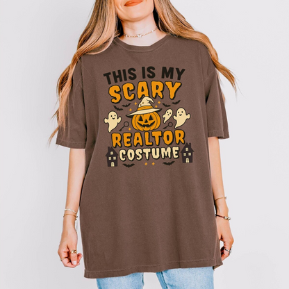 A woman wearing a brown t-shirt with a Halloween-themed design, including a jack-o-lantern, ghost, and houses.