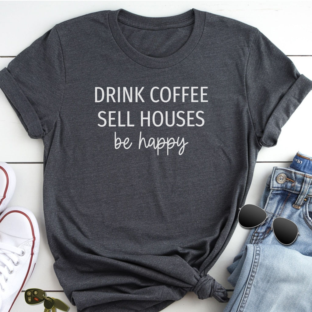 A gray t-shirt with the text "DRINK COFFEE SELL HOUSES be happy" printed on it, along with a pair of sunglasses and a pair of jeans.