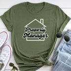 A green t-shirt with the text "Property Manager" printed on it, along with a pair of jeans and sunglasses, all laid out on a white surface.