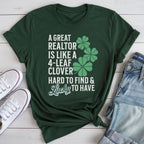 A green t-shirt with white text and a graphic of four-leaf clovers, along with a pair of jeans and white sneakers, all laid out on a white surface.
