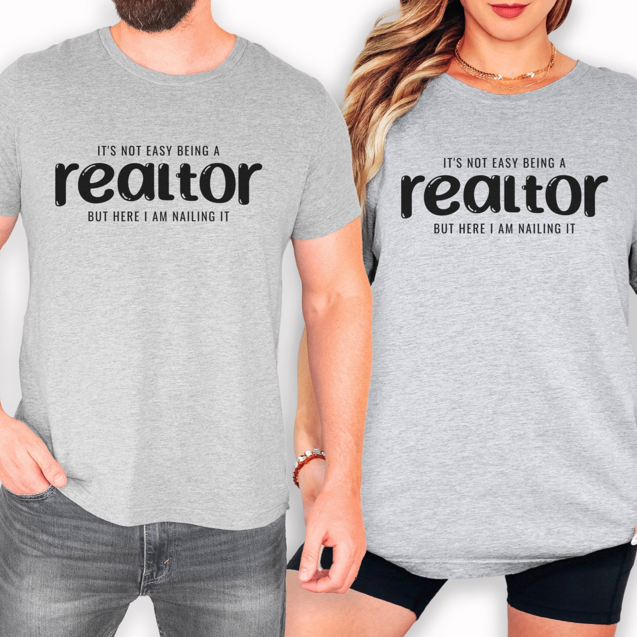 two people wearing gray t-shirts with the text "It's not easy being a realtor but here I am nailling it" printed on them.