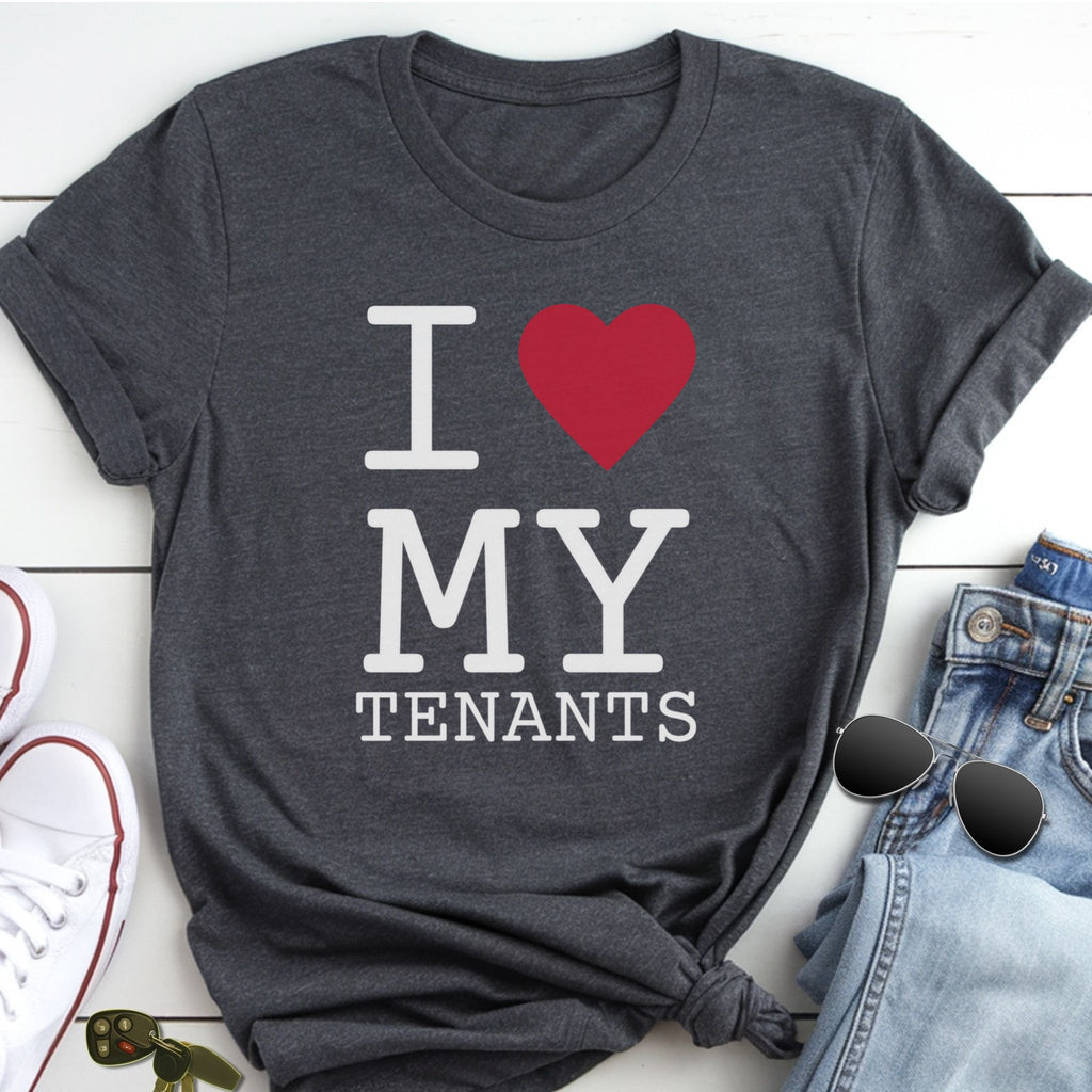 A gray t-shirt with the text "I ♥ MY TENANTS" printed on it, along with a red heart symbol. The t-shirt is placed on a white surface, and there are some jeans and sunglasses visible in the background.
