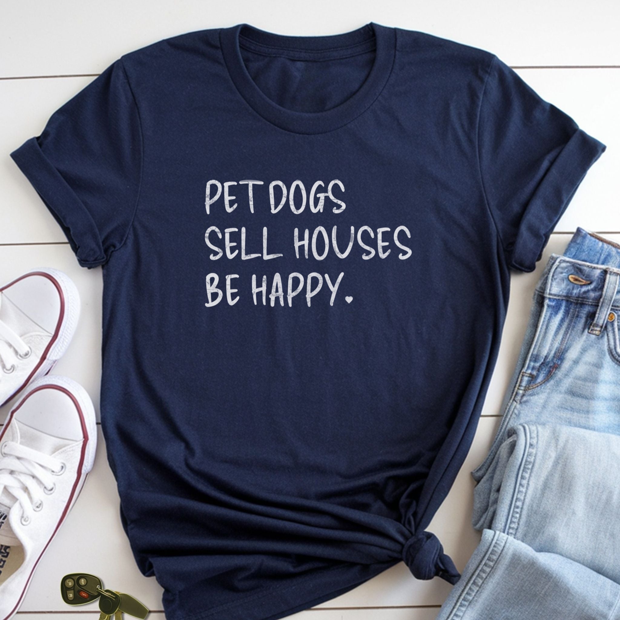 A navy blue t-shirt with the text "PET DOGS SELL HOUSES BE HAPPY" printed on it, along with a pair of jeans and white sneakers.