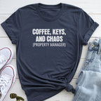 A navy blue t-shirt with the text "COFFEE, KEYS, AND CHAOS (PROPERTY MANAGER)" printed on it, along with a pair of jeans and white sneakers.