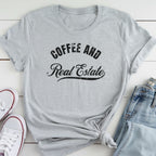 A gray t-shirt with the text "COFFEE AND REAL ESTATE" printed on it, along with a pair of jeans and white sneakers.