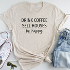 A beige t-shirt with the text "DRINK COFFEE SELL HOUSES be happy" printed on it, along with a pair of jeans and white sneakers.