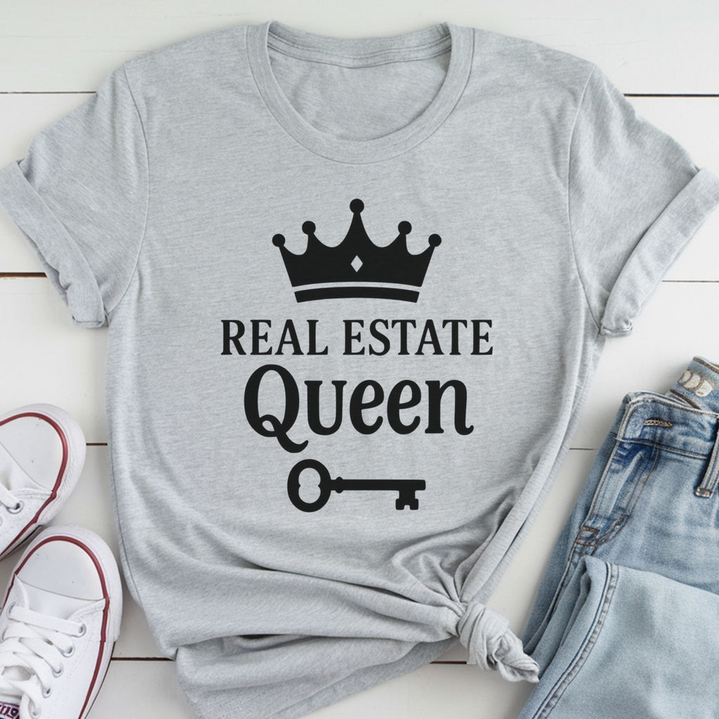 A gray t-shirt with the text "REAL ESTATE QUEEN" printed on it, along with a crown icon and a key symbol.
