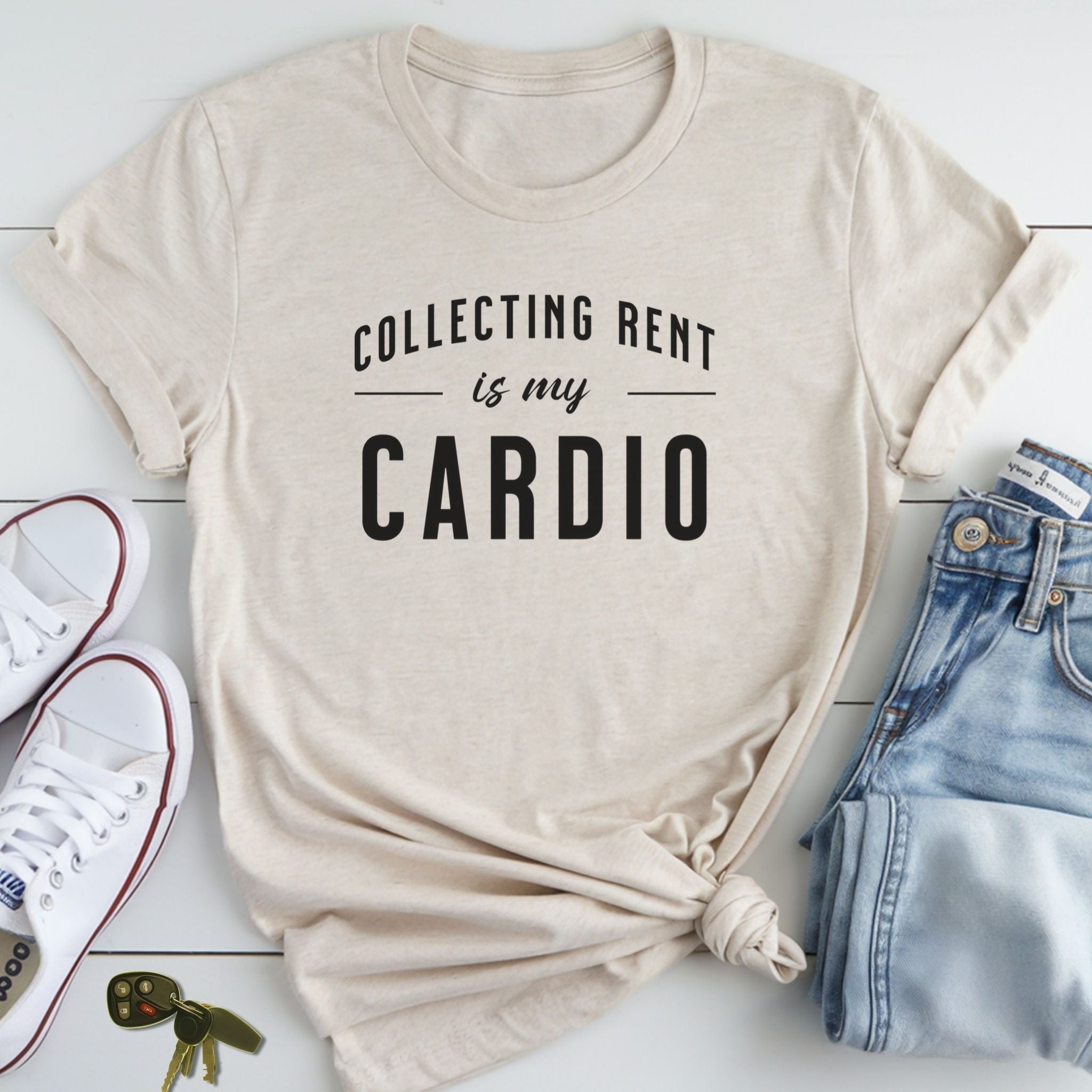 A beige t-shirt with the text "COLLECTING RENT IS MY CARDIO" printed on it, along with a pair of jeans and sneakers.