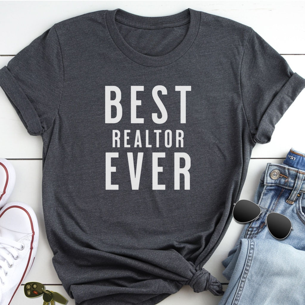 A gray t-shirt with the text "BEST REALTOR EVER" printed on it, along with a pair of jeans and sunglasses.