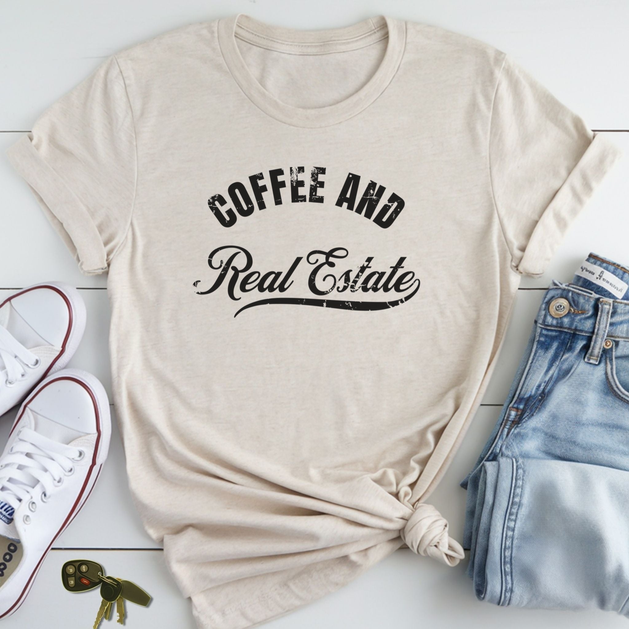 A beige t-shirt with the text "COFFEE AND REAL ESTATE" printed on it, along with a pair of jeans and white sneakers.